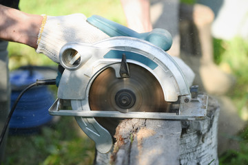 Man is cutting a wooden bar by a circular saw. Woodwork.