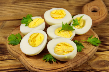 Boiled eggs with parsley on cutting board on a wooden table