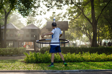 Senior man exercising hula hoops with bottle of water on top of his head in the park. © bignai