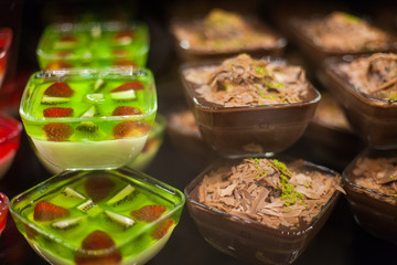 berry fruit and chocolate jelly with fresh berries in the glass topped mint leaf in display at a street food market - summer dessert