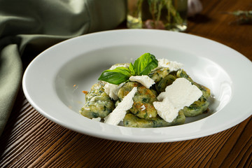 Green Gnocchi with basil, spinach, pesto feta cheese in composition with green cloth and olive oil. Close up, selective focus. Traditional italian cuisine.