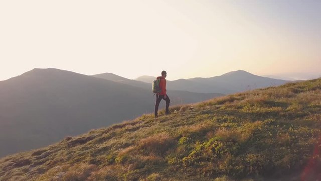 Tourist hiker with a backpack in orange jacket walking on mountain path in Carpathian mountains.