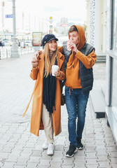 Happy young couple in love teenagers friends dressed in casual style walking together on city street in cold season