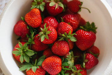 Organic fresh strawberries lying in a white bowl, close-up