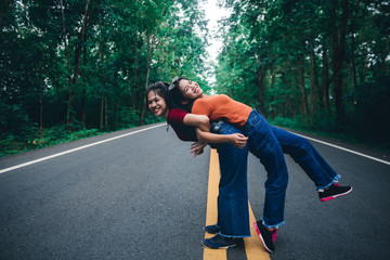 Cute Asian young girl on a piggy back ride with her sister, natural travel concept