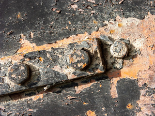 Typical detail of antique metal panel of an Italian rural house, in iron with rust, cracked paint and detail of rusted bolts.