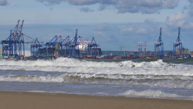 Container Terminal Cranes on Baltic Sea with Heavy Waves Splashing into Shore