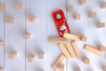 The red toy car overcomes all obstacles in the way and barriers reaching the goal and knocking down obstacles in its path. A red car rides and knocks down wooden poles in its path.