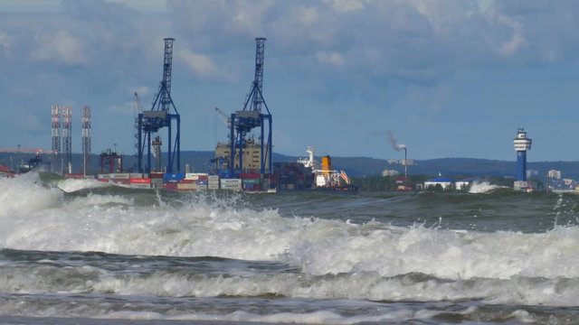 Container Terminal Cranes on Baltic Sea with Heavy Waves Splashing into Shore