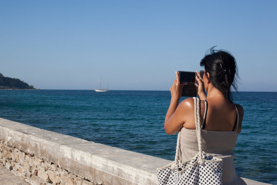 beautiful young girl, photographing a beautiful panorama on the seafront, on a sunny day