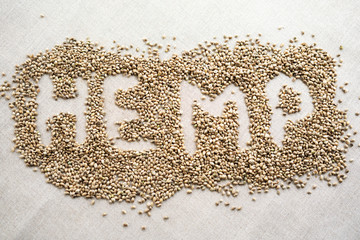 Word HEMP made of hemp seeds on linen background. Healthy eating supplement. Superfood concept. Top view.
