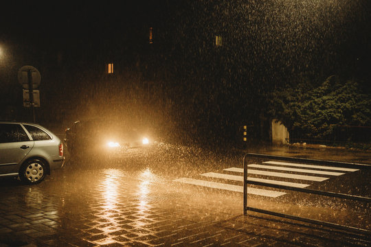 Car With Lights On At Night Crossing Zebra Pedestrian Crossing In Heavy Poordown Rain Storm 