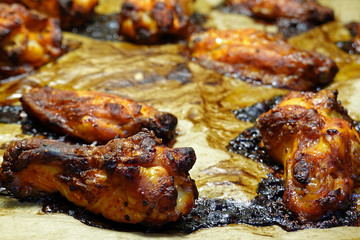 Close up of roasted spicy chicken wings on baking tray and cooking paper. Selective focus.