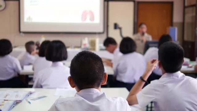 Asian classroom teaching of high school students in white uniform are actively studying science by raising their hands to answer questions that teachers ask them.