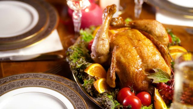 Closeup 4k panning footage of wooden table in living room with glasses of champagne, ornate dishes, candles and tasty baked turkey. Dining table served for big family on winter holidays and