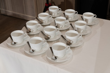 Fototapeta na wymiar many white cups of tea on the table in the restaurant,many empty tea cups. white tea mugs and saucers lined up in rows on the table