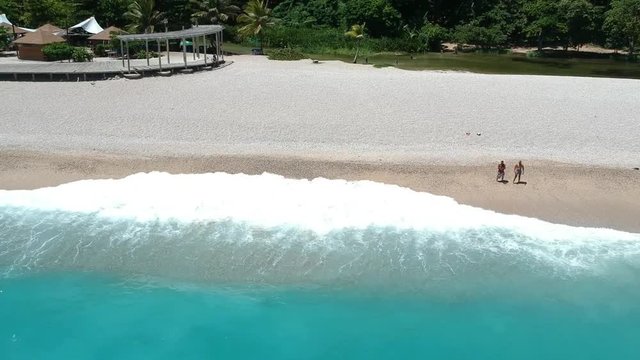 Drone flying toward the beach over warm blue water of the Caribbean of the coast of the Dominican Republic.  Small beach town of Los Patos is a favorite location for locals.