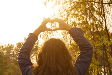 Young woman making heart - shape symbol with her hands.