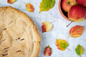Fresh baked crabapple pie displayed with apples and autumn leaves