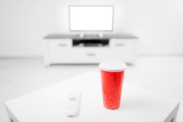 Soda juice and remote controller in the living room with a modern TV.