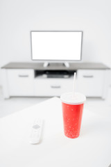 Soda juice and remote controller in the living room with a modern TV.