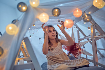 Little girl playing and making a house tent in the room.