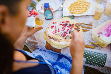 People making a picnic with sweet waffle and pancaces in the garden.