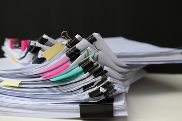 Closeup of a pile of working papers with black clips and other stationary.