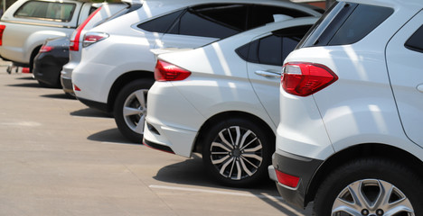 Closeup of rear side of white car with  other cars parking in outdoor parking area.