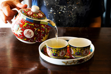 Chinese tea is poured into a glass of hot tea in a teapot.