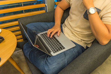 Human comfortably sitting on armchair and using laptop at home