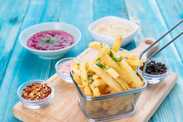 Fries Potato in Basket with Hommos and Red Hommos, Fried Potato with Spices and Arabic Hommos / Hummus / Hummus. On Blue Wood Background