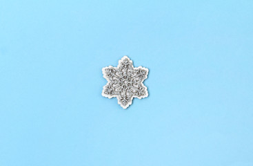 Wooden glittering snowflakes on blue pastel background.