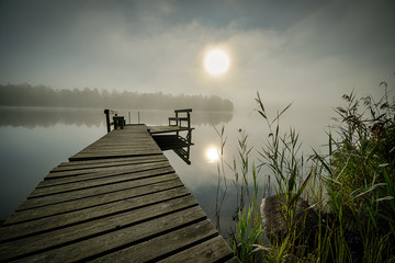 Mysterious foggy landscape with wooden bridge