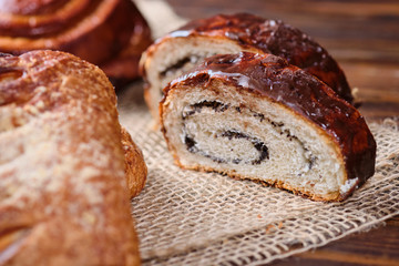 puff buns with jam and raisins in the shape of a snail on burlap and wooden background. Close-up