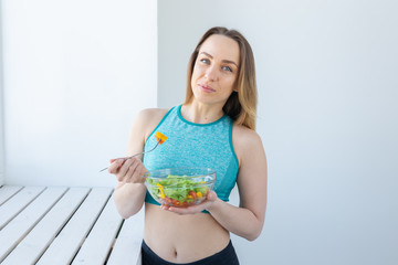 Healthy lifestyle, fitness and diet concept - dietary salad and woman in sports wear