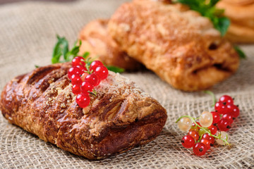 puffs with berry filling with sprigs of fresh red and white currants on burlap and dark wooden background. Close-up. Selective focus