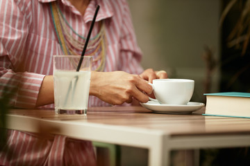 Attractive mixed race woman sitting in cafe and enjoying her coffee.