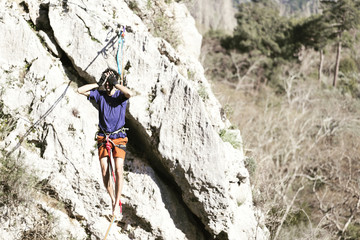 Fototapeta premium A man is walking along a stretched sling. Highline in the mountains. Man catches balance. Performance of a tightrope walker in nature. Highliner on the background of the mountains.