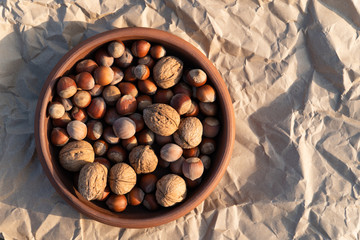 clay plate with nuts of different grades on a background of crumpled craft paper