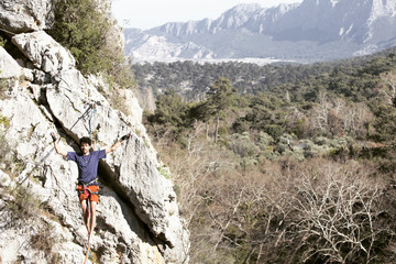 A man is walking along a stretched sling. Highline in the mountains. Man catches balance. Performance of a tightrope walker in nature. Highliner on the background of the mountains.
