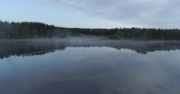 Aerial shot of flying above calm lake and swamp in Finland.