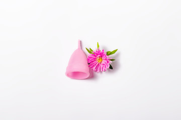 Obraz na płótnie Canvas Pink menstrual cup and flower on a white background. Concept of menstruation, the choice between feminine hygiene products. Flat lay, top