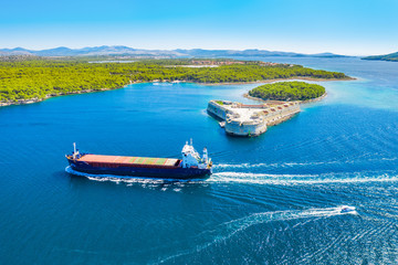 Old stone St. Nicholas fortress at Sibenik bay entrance, archipelago od Dalmatia, Croatia, freighter ship passing by 