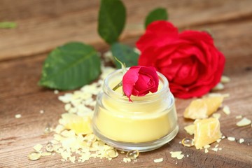 Obraz na płótnie Canvas Homemade natural lip balm. Made from beeswax, sheabutter, olive and coconut oil mixed together, decorated with rose