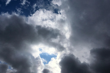 Big dark dramatic fluffy clouds in the blue sky on sunny light. Abstract nature background.