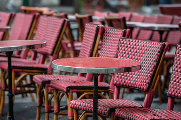Fototapeta na wymiar Parisian café terrace with red rattan furniture a rainy day