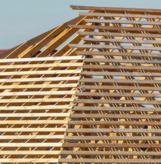 Workers are building the roof of the house from wood