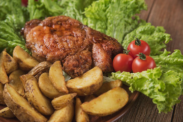 pork steak with fried potatoes on lettuce leaves with cherry tomatoes