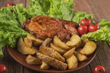 pork steak with fried potatoes on lettuce leaves with cherry tomatoes